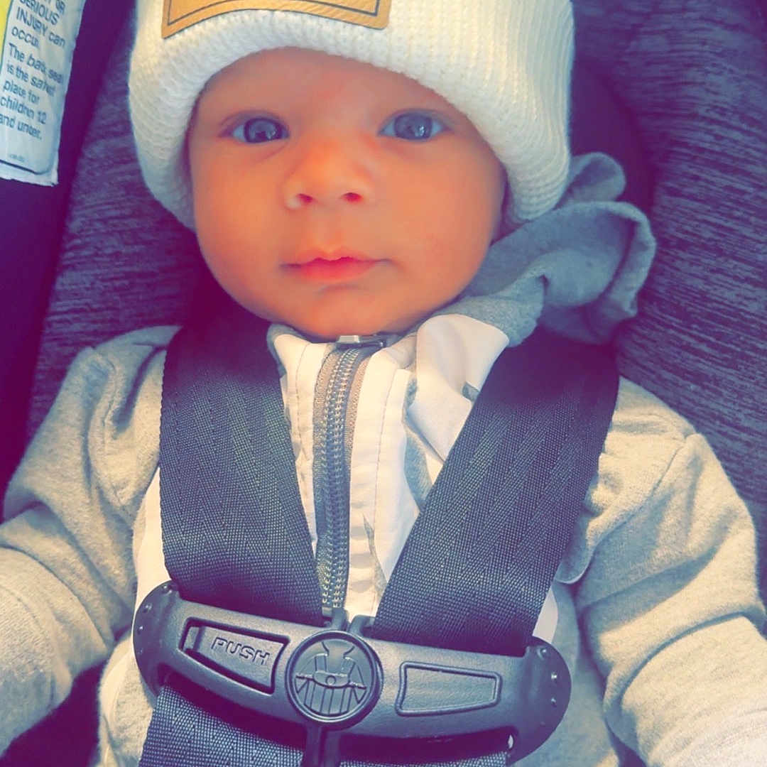 Coehn is registered to the contest to win money with this photo: accessories, baby, baseballcap, belt, bonnet, cap, clothing, coat, face, glove, hat, head, jacket, pants, person, photography, portrait, seatbelt, transportation, vehicle