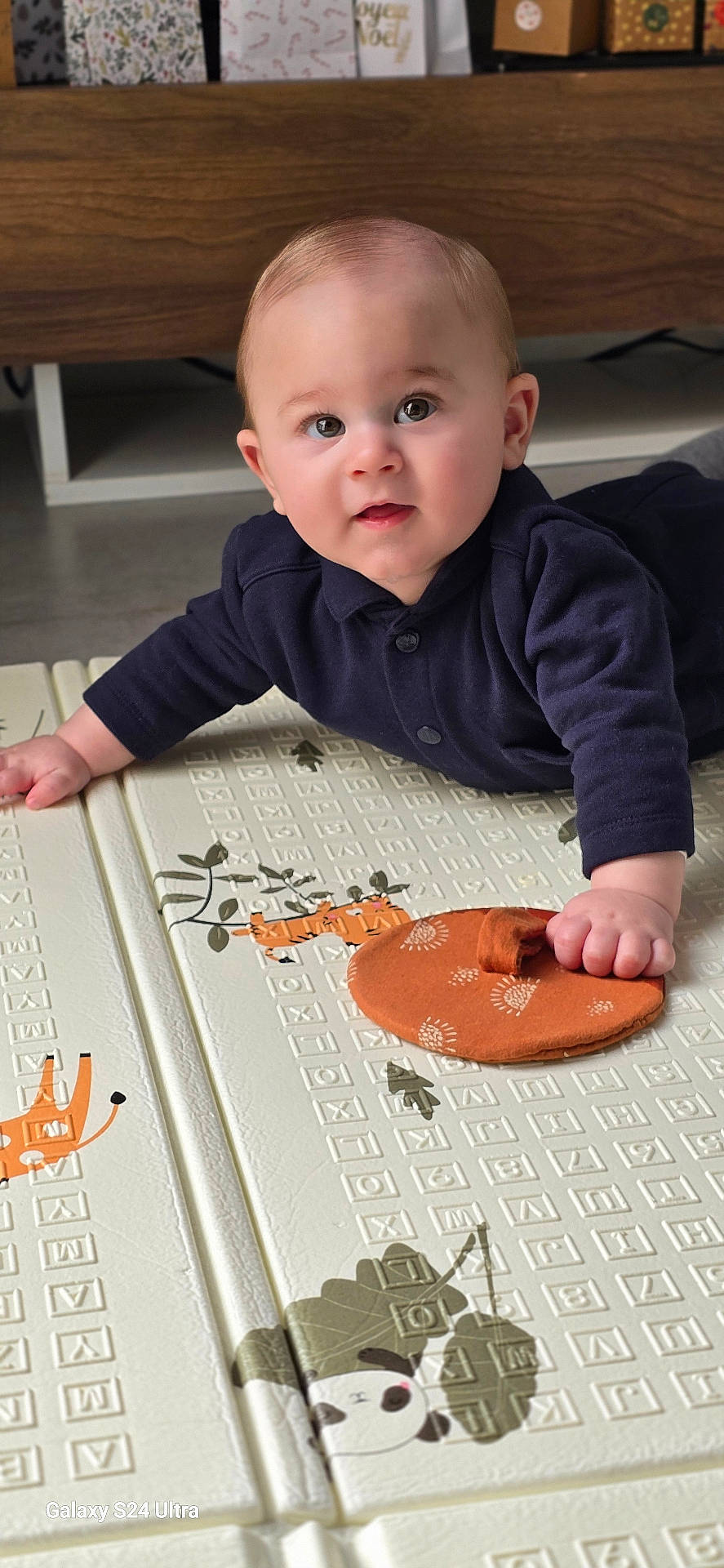 Pablo participe au concours pour gagner de l'argent avec cette photo : applique, baby, bodypart, clothing, crawling, face, finger, footwear, furniture, hand, head, pants, pattern, person, photography, portrait, shoe, sitting, t_shirt, wood