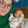 Colt joined the competition — help win amazing prizes! adult, baby, newborn, hospital, medical_equipment, glasses, green_shirt, blanket, baby_wrapped, nasal_cannula, tattoo, arm, person, indoor, portrait, bed, healthcare, care, smile, closeup