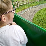 Aureline a rejoint le concours — aidez-le/la à gagner de superbes lots ! child, glasses, white_shirt, green_ride, amusement_park, track, grass, fence, people, outdoor, daylight, curly_hair, seat, nature, relaxing, group, leisure, summer, casual, fun