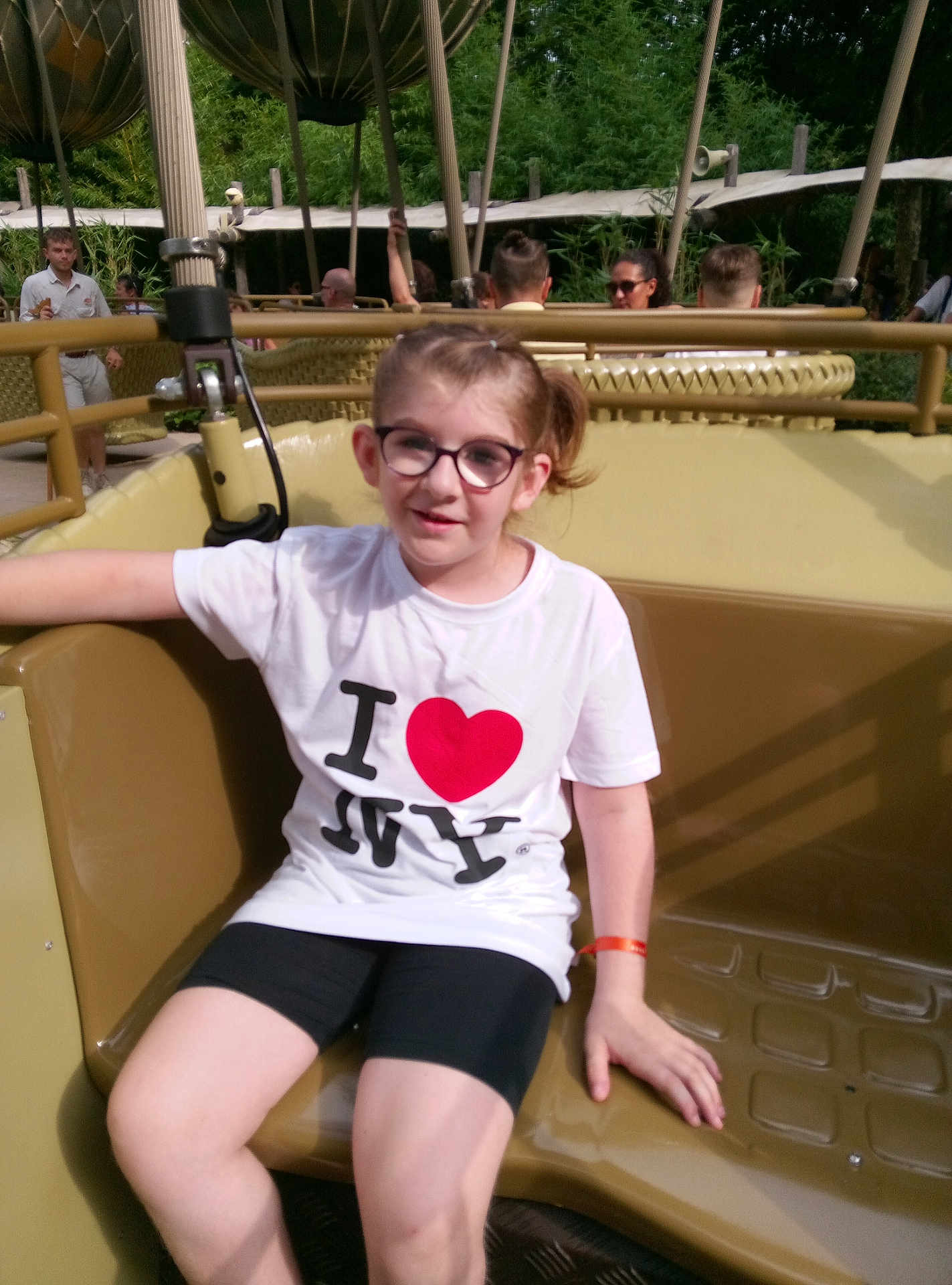Aureline participe au concours pour gagner de l'argent avec cette photo : child, glasses, tshirt, shorts, amusement_ride, seat, outdoor, daylight, greenery, people, smile, casual_clothing, park, happy, young, person, relaxed, summer, fun, leisure