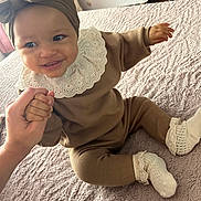 Yaëlle a rejoint le concours — aidez-le/la à gagner de superbes lots ! baby, bed, blanket, brown_outfit, child, crib, cute, furniture, happy, headband, holding_hand, indoor, infant, nursery, person, portrait, smiling, socks, textile, white_lace