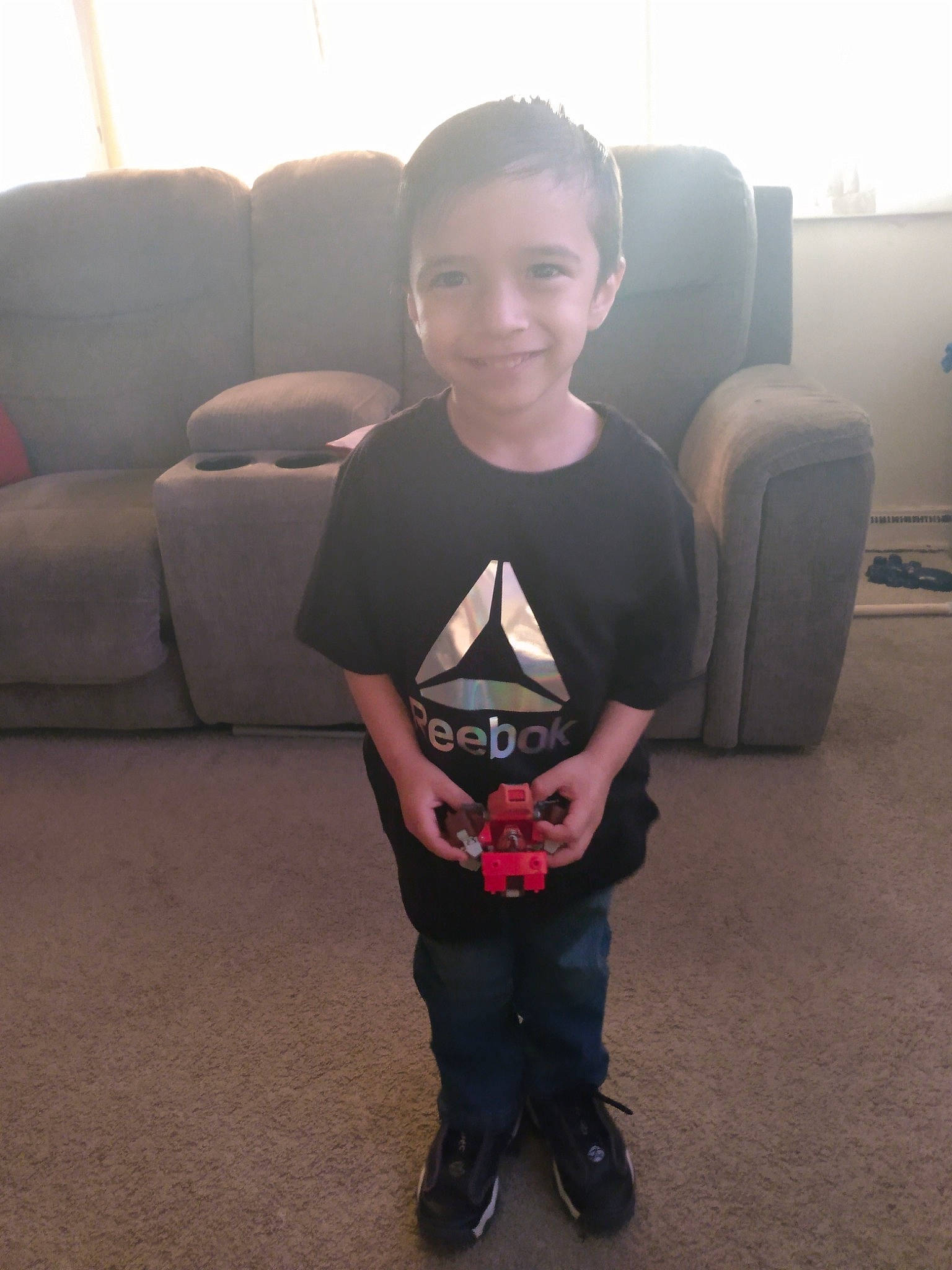 Connor is registered to the contest to win money with this photo: child, comfort, electronic_device, face, floor, flooring, fun, hair, hairstyle, head, human_body, joint, joy, leg, mouth, person, shoe, sitting, sleeve, smile