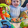 Logan is registered to the contest to win money with this photo: baby, bodypart, chair, cushion, cutlery, face, finger, furniture, hand, happy, head, homedecor, indoors, person, photography, playarea, portrait, sitting, spoon, toy