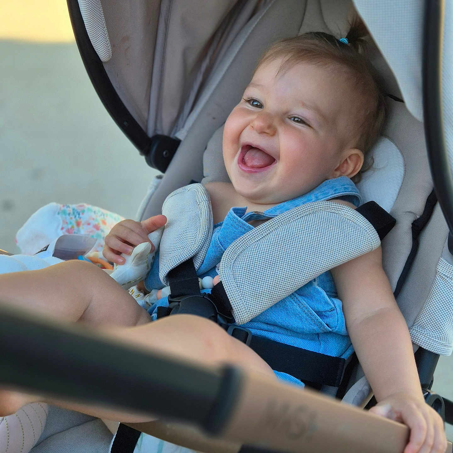 Swanne participe au concours pour gagner de l'argent avec cette photo : baby, baby_harness, blue_clothing, candid, child, cute, diaper, face, hand, happy, infant, joyful, outdoor, person, portrait, seatbelt, smiling, stroller, sunlight, young_child