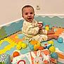 baby, child, smiling, play_mat, toys, balls, colorful, indoor, happy, sitting, cute, soft_toys, infant, clothing, face, person, floor, playtime, young_child, room