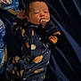 Grimm joined the competition — help win amazing prizes! baby, infant, onesie, space_theme, blanket, sleepwear, hand, face, lying_down, bed, comfort, dark_blue, patterned_clothing, newborn, cute, child, indoors, portrait, resting, soft