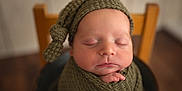 Jayce joined the competition — help win amazing prizes! newborn, baby, sleeping, knitted_hat, blanket, infant, peaceful, portrait, closeup, soft_focus, wooden_chair, wrapped, child, indoors, cute, skin, hand, peace, rest, warm_tones