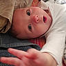 James is registered to the contest to win money with this photo: baby, child, face, hand, blue_eyes, blanket, bed, pillow, white_clothing, infant, closeup, skin, cute, young, expression, reaching, person, indoors, soft_texture, cozy