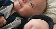James is registered to the contest to win money with this photo: baby, smile, face, infant, hand, pillow, clothing, cute, portrait, closeup, skin, child, person, young, indoor, soft, happy, expression, head, hair