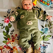 Denzel participe au concours pour gagner de l'argent avec cette photo : baby, child, infant, green_clothing, bear_pattern, knitwear, hat, boots, toy, rattle, blanket, animal_print, giraffe, monkey, rhino, elephant, floor, playtime, cute, portrait