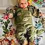 baby, child, infant, green_clothing, bear_pattern, knitwear, hat, boots, toy, rattle, blanket, animal_print, giraffe, monkey, rhino, elephant, floor, playtime, cute, portrait