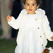Juliette a rejoint le concours — aidez-le/la à gagner de superbes lots ! toddler, child, white_dress, quilted_jacket, outdoor, grass, dog, pet, curly_hair, portrait, person, cute, young_child, winter_clothing, standing, animal, background_people, fashion, happy, innocent