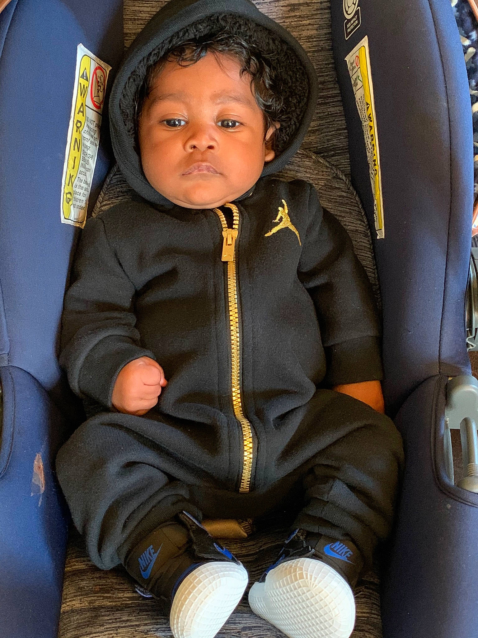 Draylen is registered to the contest to win money with this photo: auto_part, black_hair, car_seat, cheek, child, eye, face, fun, head, jacket, jeans, outerwear, person, sitting, skin, smile, toddler