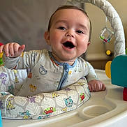 Briggs joined the competition — help win amazing prizes! activity_center, baby, child, clothing, colorful, cute, drool, expression, face, furniture, happy, indoor, infant, onesie, play, portrait, seat, smiling, toy, young