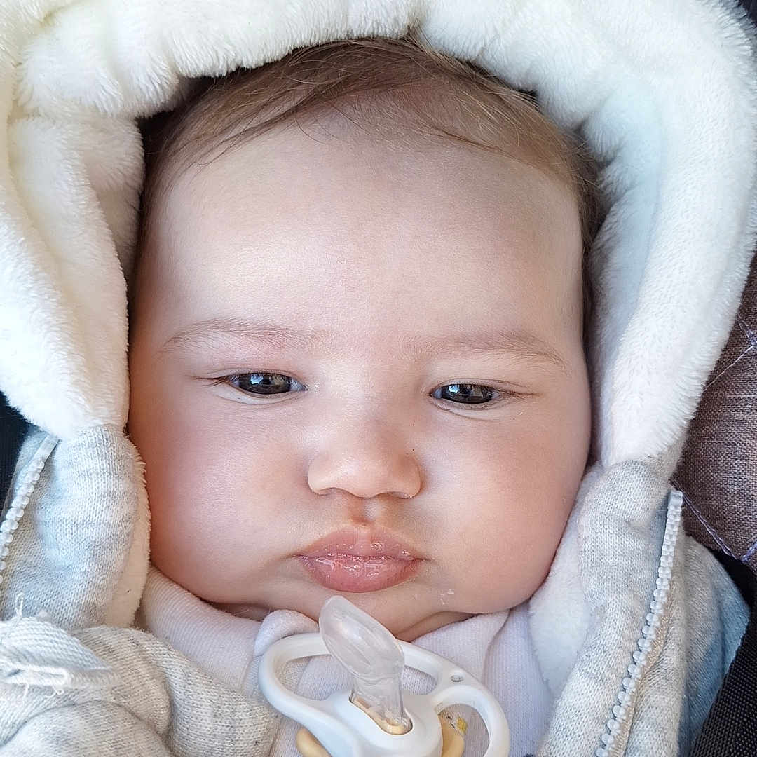 Nour participe au concours pour gagner de l'argent avec cette photo : baby, bundle, child, closeup, clothing, cozy, cute, expressionless, face, hood, indoors, infant, jacket, pacifier, portrait, skin, small, soft, warm, young