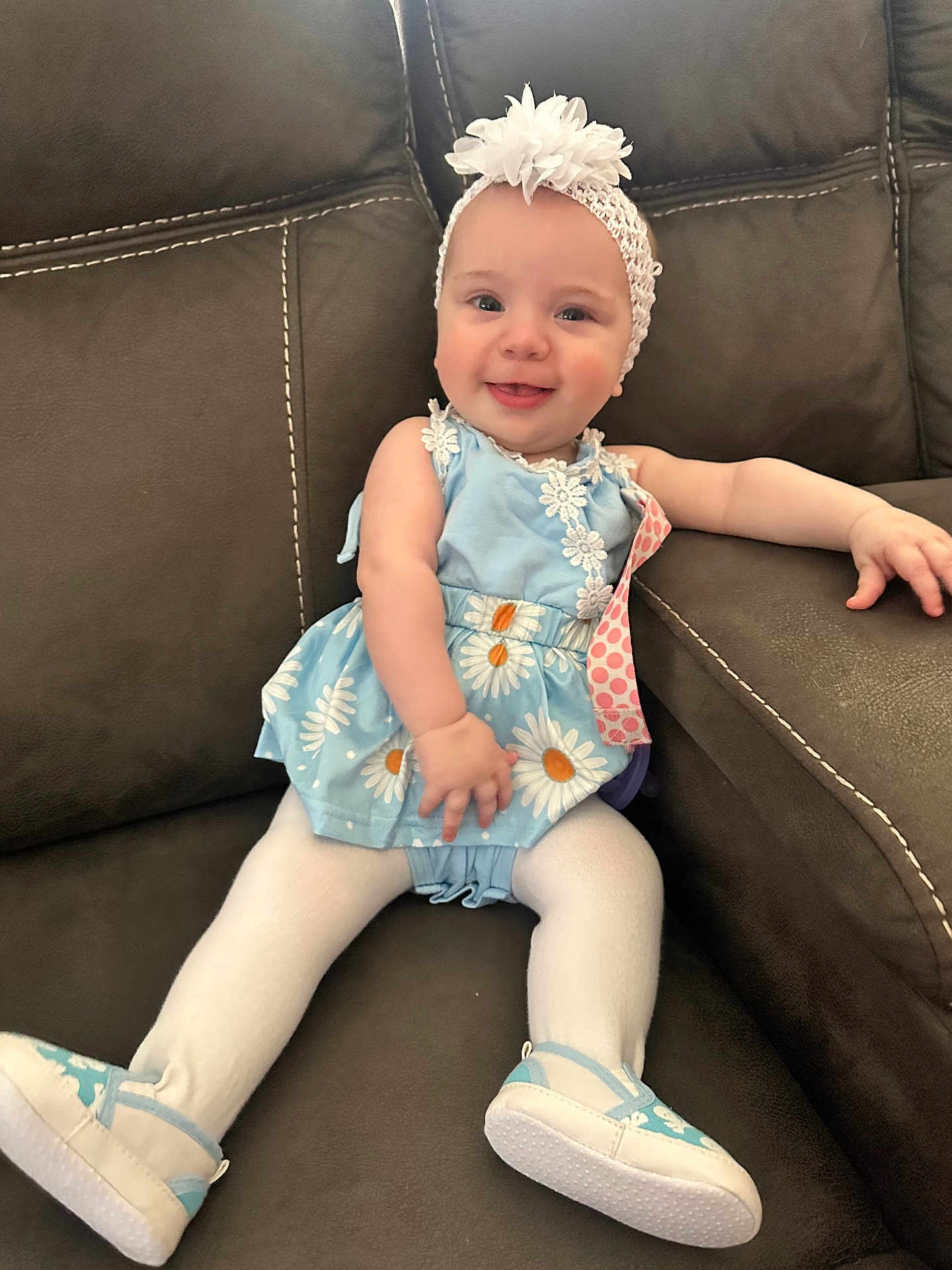 Kourtney is registered to the contest to win money with this photo: baby, bonnet, cap, clothing, couch, cushion, dress, face, footwear, furniture, happy, hat, head, pants, person, photography, portrait, shoe, sitting, sneaker
