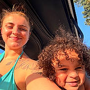 Kashton Purcell is registered to the contest to win money with this photo: woman, child, smile, tattoo, curly_hair, sunlight, outdoor, blue_sky, tree, vehicle, portrait, happy, skin, face, shoulder, daylight, casual, people, nature, summer