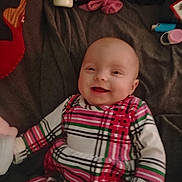 Shaina joined the competition — help win amazing prizes! baby, smile, infant, striped_clothing, blanket, indoor, child, happy, person, face, cute, lying_down, plaid_pattern, soft_toys, bottle, pink, red, green, white, cozy