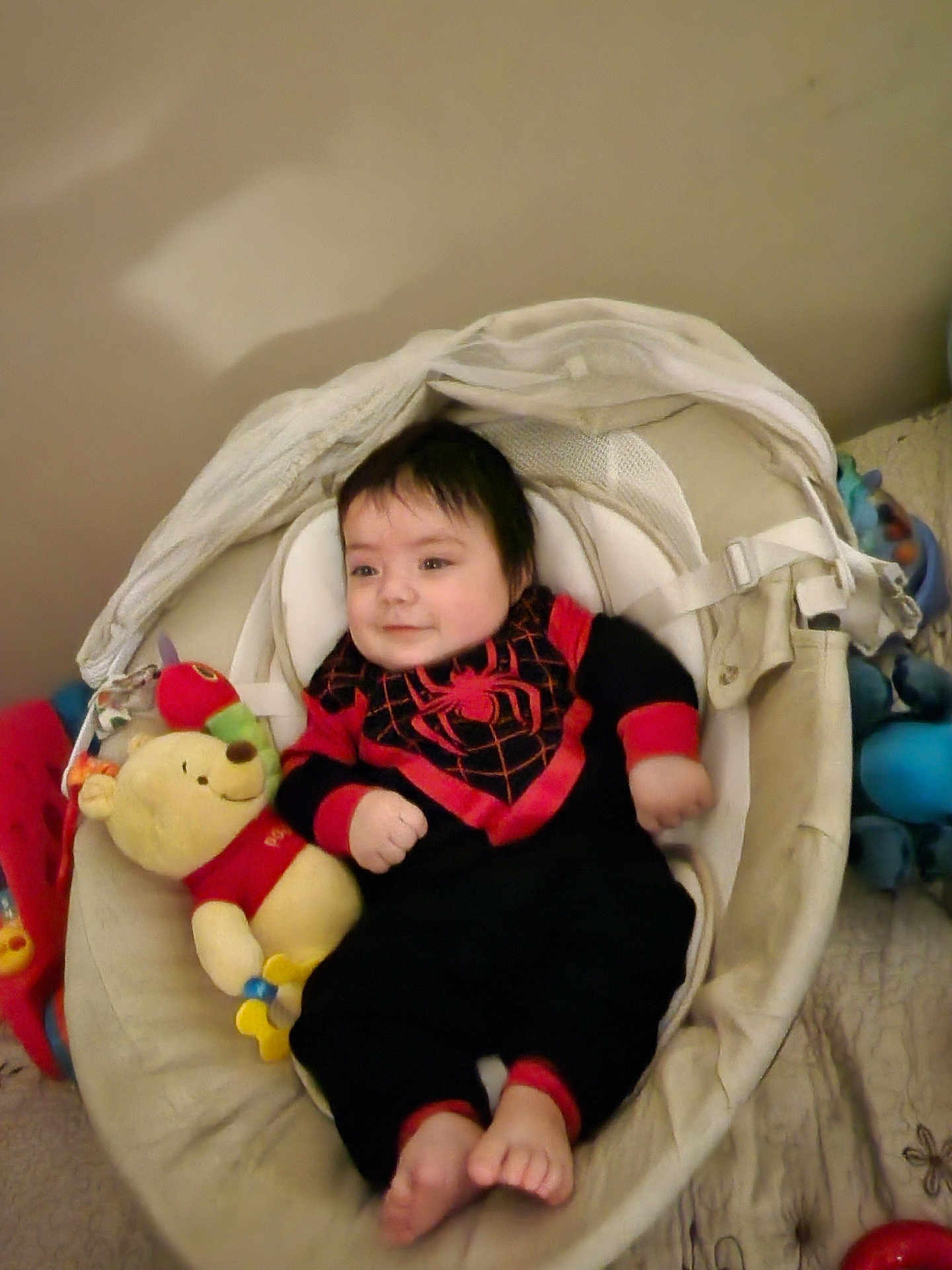 Nathanael is registered to the contest to win money with this photo: baby, infant, baby_seat, plush_toy, winnie_the_pooh, black_clothing, red_clothing, smiling, indoors, cute, child, soft_toys, cozy, happy, feet, face, person, comfort, resting, casual