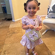 Chloe is registered to the contest to win money with this photo: child, girl, pigtails, dress, purple_dress, purse, bow, smile, indoor, floor_tiles, shoes, sandals, cute, happy, person, young_child, home_interior, standing, portrait, fashion