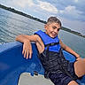 Edzio a rejoint le concours — aidez-le/la à gagner de superbes lots ! adventure, boat, boy, child, clouds, haircut, happy, lake, life_jacket, outdoors, portrait, shoreline, shorts, sitting, sky, smiling, summer, trees, vacation, water