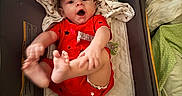 Beau joined the competition — help win amazing prizes! baby, infant, red_onesie, hat, playpen, blanket, hand, smiling, happy, feet, fingers, indoor, soft_lighting, human_interaction, cute, child, person, fabric, bedroom, resting