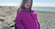 Rubie Jean is registered to the contest to win money with this photo: casual_clothing, child, colorful_leggings, daylight, girl, happy, leisure, nature, ocean, outdoor, pebbles, pink_jacket, portrait, rocky_beach, sky, smiling, standing, vacation, windy, young
