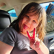 Rubie Jean is registered to the contest to win money with this photo: automobile, car_interior, casual_clothing, child, daylight, fun, girl, happy, inside, messy_hair, peace_sign, person, playful, portrait, seat, seatbelt, sunlight, tongue_out, window, young