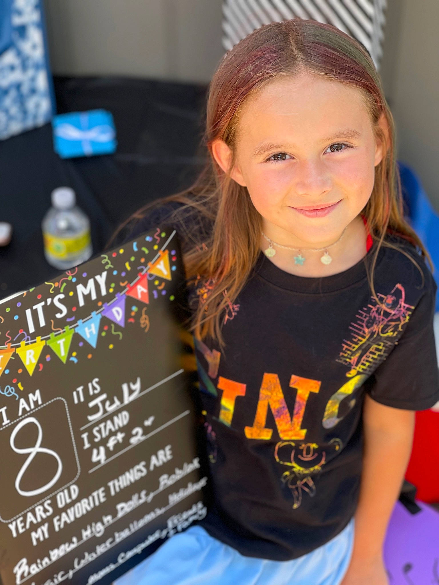 Taylynn joined the competition — help win amazing prizes! blond, chair, child, distilled_beverage, event, face, fun, happy, head, headpiece, joy, leisure, long_hair, party, person, product, recreation, room, smile, t_shirt