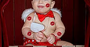 Noah is registered to the contest to win money with this photo: angel_wings, baby, child, costume, grass, humorous, indoor_set, infant, kissing_booth, lipstick_kisses, photography, portrait, prop, red_bow_tie, red_curtains, smiling, tickets, white_feather, wooden_booth, wooden_sign