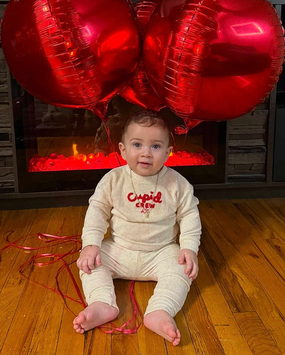 Noah joined the competition — help win amazing prizes! baby, infant, child, red_balloons, heart_balloons, onesie, cupid_crew, fireplace, hardwood_floor, sitting, ribbon, toes, smile, face, portrait, indoor, cozy, valentines, reflection, cute