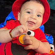 Noah is registered to the contest to win money with this photo: baby, child, smiling, red_hat, elmo_shirt, plush_toy, happy, cute, portrait, indoor, closeup, face, hands, infant, red_clothing, playing, fun, joy, bright_colors, soft_toy