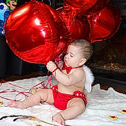 Noah is registered to the contest to win money with this photo: angel_wings, baby, child, cozy, cupid_costume, festive, fireplace, heart_balloons, heart_cookies, indoor, infant, luigi_plush, photography, portrait, red_balloons, red_outfit, sitting, stuffed_toy, valentines_day, white_blanket