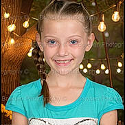 Lola joined the competition — help win amazing prizes! girl, child, portrait, smile, braid, blue_shirt, string_lights, tree, forest_background, watermark, studio_portrait, face, blue_eyes, teeth_gap, long_hair, ear, neck, shoulders, happy, close_up