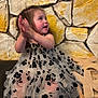 Miyrah joined the competition — help win amazing prizes! toddler, child, clapping, dress, floral_pattern, black_and_white, stone_wall, wooden_decoration, sitting, happy, indoor, cute, smiling, person, young_child, celebration, clothing, portrait, furniture, texture