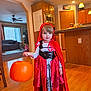 Giana joined the competition — help win amazing prizes! cabinet, child, costume, curtains, cute, door, floor, halloween, holiday, indoor, kitchen, lamp, living_room, microwave, person, pumpkin_bucket, red_cape, socks, toy, wood_floor