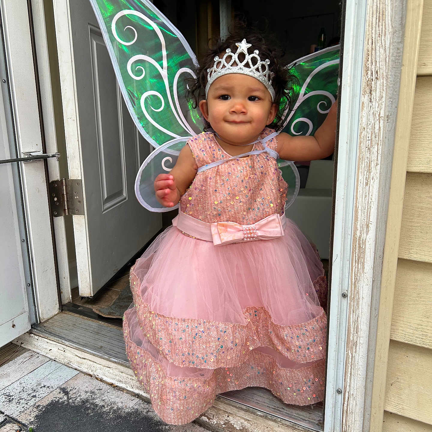 Amylah is registered to the contest to win money with this photo: child, costume, curly_hair, cute, doorway, dress, fairy_wings, footwear, headband, home, indoor, magic, person, pink_dress, playful, portrait, smiling, sparkles, tiara, young_child