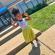 Kha'Lisia joined the competition — help win amazing prizes! child, girl, outdoor, sunny_day, sidewalk, steps, grass, building, window, shadow, pose, smiling, colorful_clothing, sneakers, hair_puff, playful, young, happy, daylight, casual