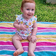 Emery is registered to the contest to win money with this photo: baby, child, smiling, outdoor, grass, towel, colorful, striped, romper, sitting, happy, cute, person, skin, foot, hand, nature, daylight, portrait, young