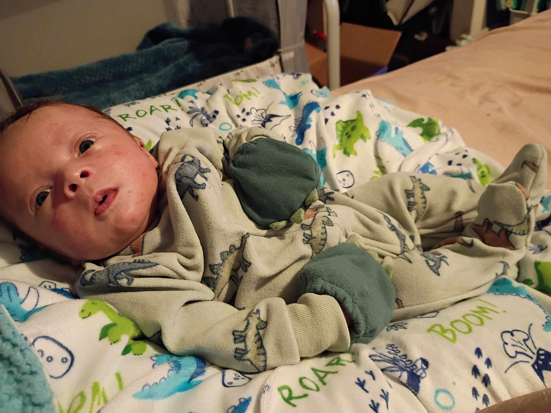 Kingston joined the competition — help win amazing prizes! baby, infant, pajamas, dinosaur_print, blanket, bed, clothing, face, person, indoor, cute, soft, sleepwear, child, newborn, resting, colorful, pattern, warm, comfort