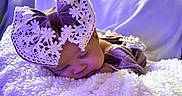 Kailani is registered to the contest to win money with this photo: baby, sleeping, bow, lace, blanket, purple_light, cozy, soft_texture, infant, headwear, cute, peaceful, rest, closeup, portrait, indoors, fabric, snuggled, child, toddler
