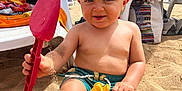 Lyam participe au concours pour gagner de l'argent avec cette photo : toddler, beach, sand, toy, shovel, cap, sunny, child, play, outdoor, barefoot, smiling, summer, vacation, sand_toys, plastic_toy, umbrella, chair, relaxation, holiday