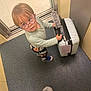 Noam a rejoint le concours — aidez-le/la à gagner de superbes lots ! child, glasses, suitcase, floor, elevator, door, plastic_wrap, blue, standing, looking_up, person, footwear, carpet, handle, travel, young_child, indoor, curious, round_glasses, clothing