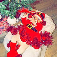 Shelsy a rejoint le concours — aidez-le/la à gagner de superbes lots ! baby, christmas_tree, red_clothing, santa_hat, ornaments, tinsel, blanket, floor, holiday, festive, infant, decorations, cute, child, indoors, celebration, seasonal, festivity, toy, cozy