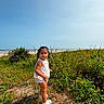 child, toddler, girl, portrait, outdoor, beach, ocean, seaside, wildflowers, flowers, meadow, grass, sunny, sky, waves, nature, summer, standing, clothing, shoes