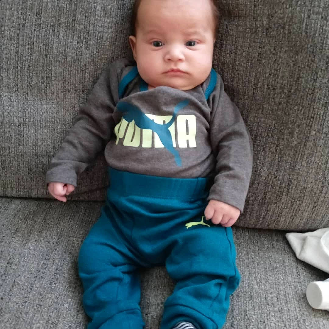 Karsen is registered to the contest to win money with this photo: arm, baby, baby_toddler_clothing, cheek, child, comfort, electric_blue, facial_expression, finger, grey, head, linens, nose, outerwear, person, sitting, skin, sleeve, sportswear, t_shirt