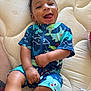 baby, child, smiling, happy, infant, blue_clothing, patterned_clothing, mattress, indoor, cute, face, hand, legs, skin, person, playful, toddler, hair, lying_down, casual