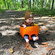 Theodore is registered to the contest to win money with this photo: autumn, baby, barefoot, beanie, child, cute, dirt_path, fall_leaves, forest, happy, nature, outdoor, plaid_shirt, pumpkin, seasonal, sitting, smiling, sunlight, woodland, young_child