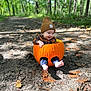 autumn, baby, barefoot, beanie, child, cute, dirt_path, fall_leaves, forest, happy, nature, outdoor, plaid_shirt, pumpkin, seasonal, sitting, smiling, sunlight, woodland, young_child